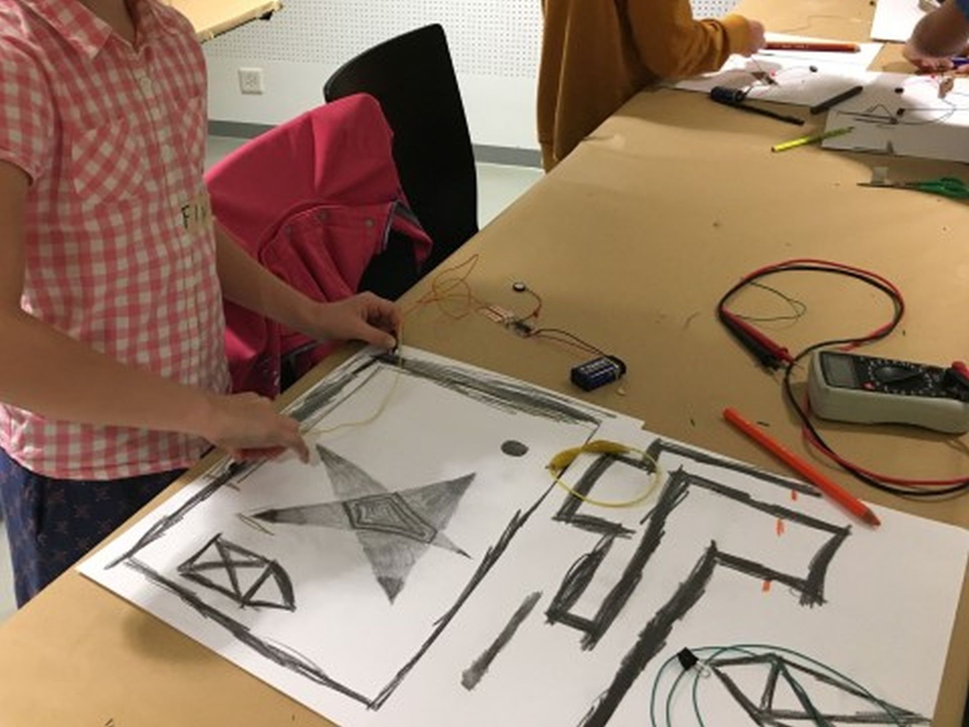 Schülerin legt Drähte auf eine Zeichnung