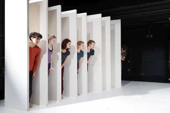 Fünf Jugendliche schauen aus einem weissen Bühnenbild hervor