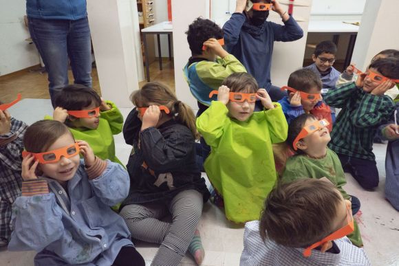 Kinder sitzen mit orangen Brillen am Boden