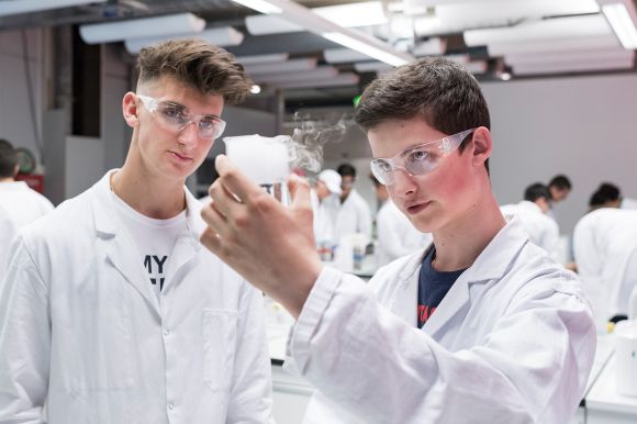 zwei Jugendliche mit Schutzbrillen und weissem Kittel in einem Labor