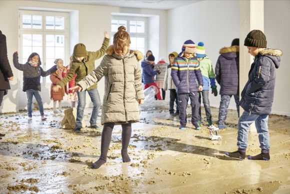 Kinder in einem Raum mit schlammigem Boden